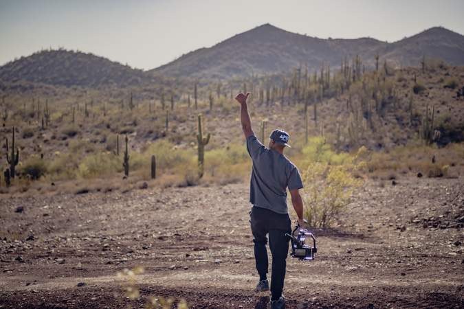 Aaron walking a desert wash with the camera, saguaros behind