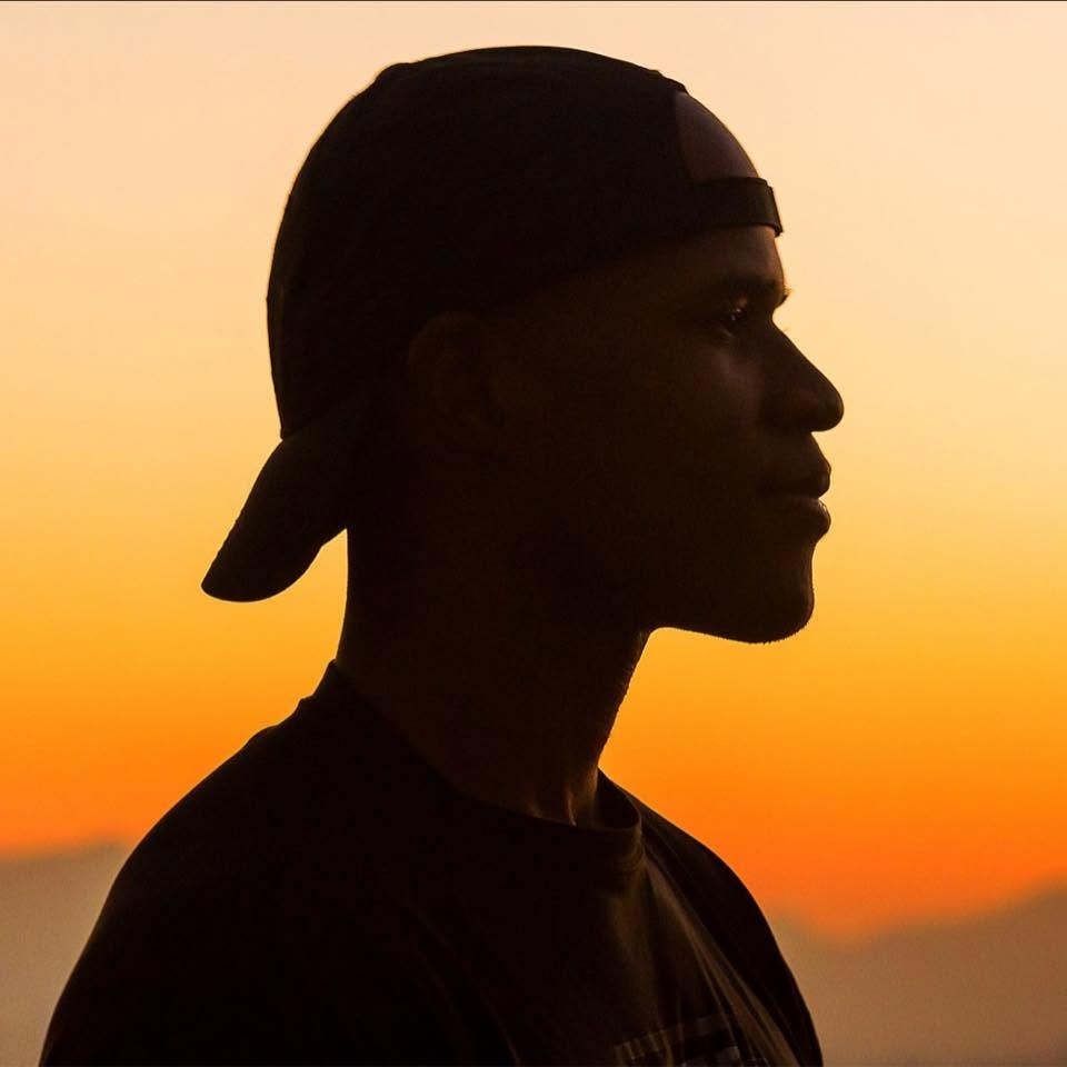 Aaron Daniels in profile, silhouetted against an orange desert sunset