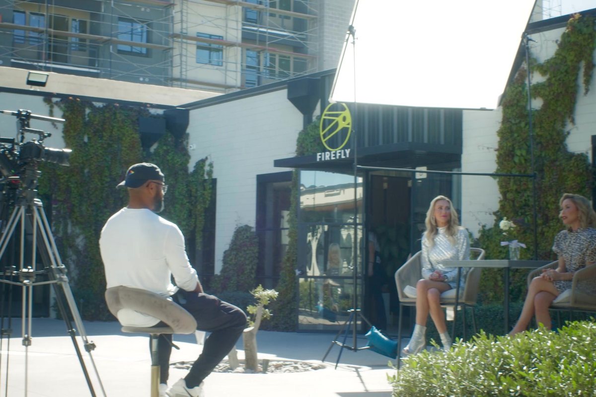 Aaron seated on the courtyard interview set, camera on the owners of Rouge & Wright