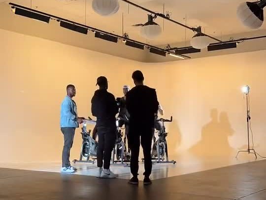 The APEX crew on the NYX Cycle set: the director and crew with the riders in front of a lit studio wall