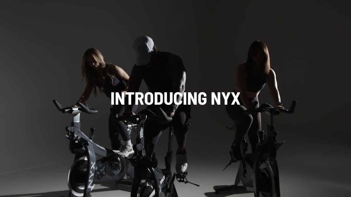 Riders silhouetted on bikes on a white cyc as the lights fade up